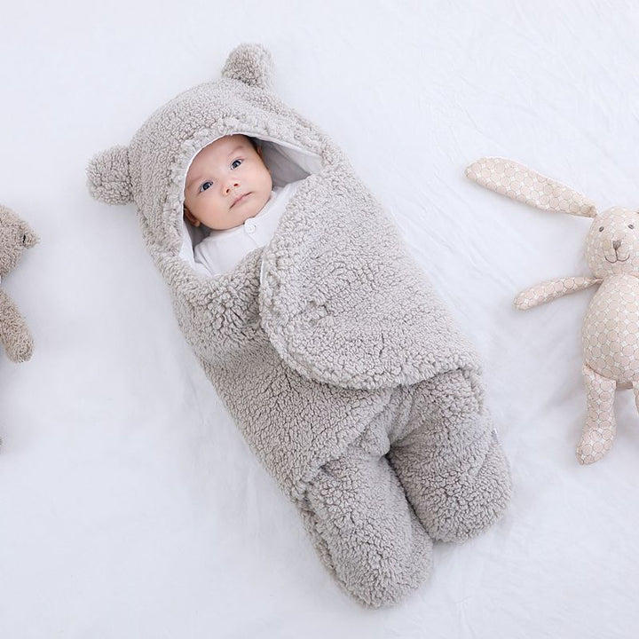 Baby i beige sovpåse med björnöron