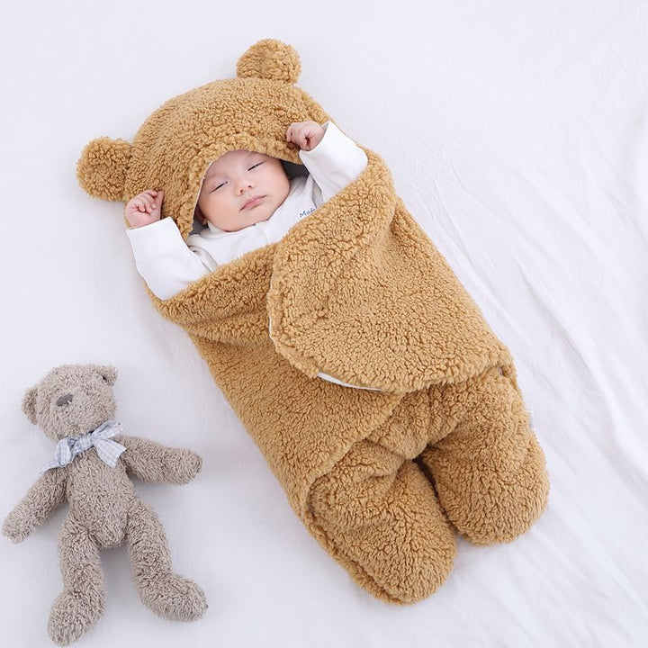 Baby i beige sovpåse med björnöron