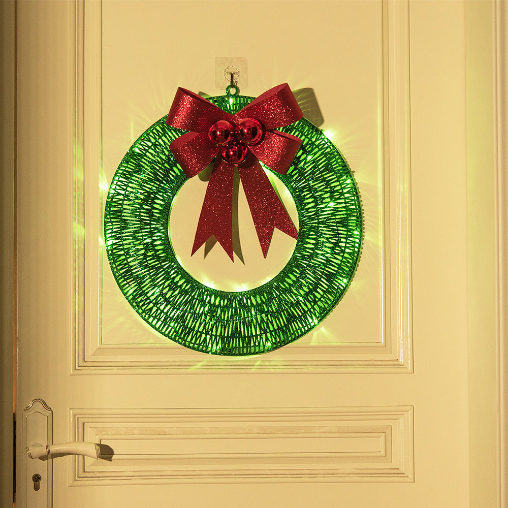 Upplyst julkrans med röd rosett på dörr